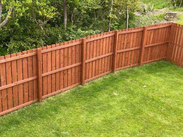 Stained wood board privacy fence around a green backyard