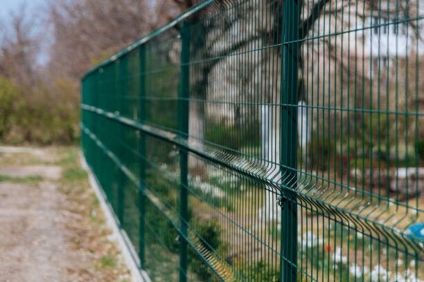 Green welded wire panel fence along a field
