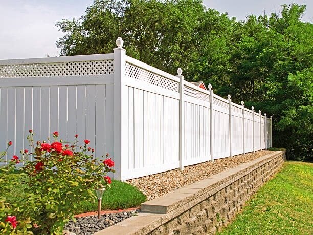White vinyl privacy fence with lattice top above a flower bed